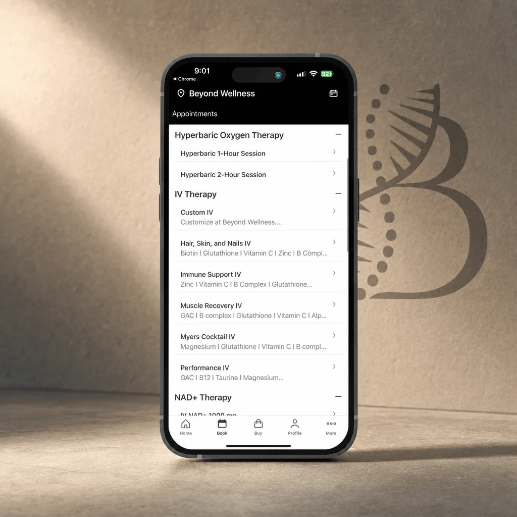 The Beyond Wellness app open on a phone, standing against a sand wall marked with the Beyond monogram.