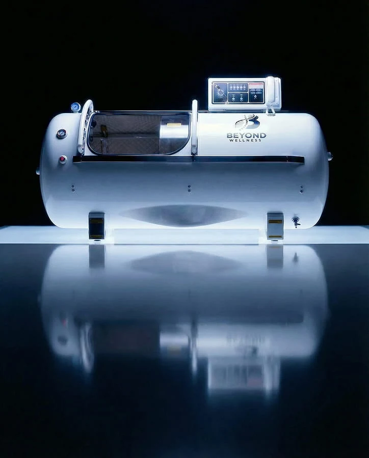 The hardshell hyperbaric chamber lit against a dark ground, its control panel visible on top.