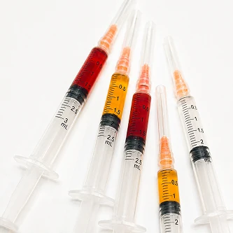 Five filled syringes laid in a row on a pale ground.