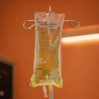 An IV bag hanging against a warm orange ground.